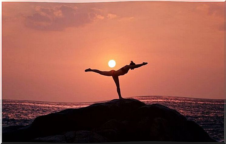 Woman performing yoga by the sea.