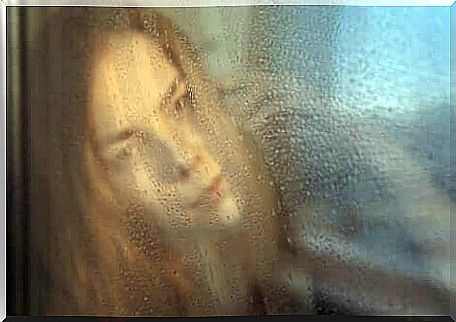 A woman looking out of a rainy window