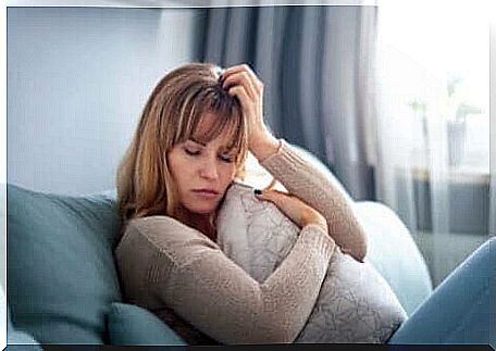 A sad woman is resting on a sofa