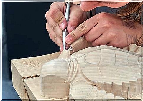 A woman carving a wooden turtle.